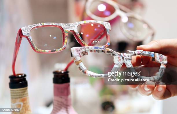 Half-finished frames for glasses and a finished pair of glasses with newspapers incorporated into the design are on display at the booth of...