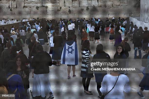 Jewish youths wrapped in Israel's national flag pray, along with fellow Israelis, at the Western Wall in Jerusalem's Old City during Jerusalem Day...