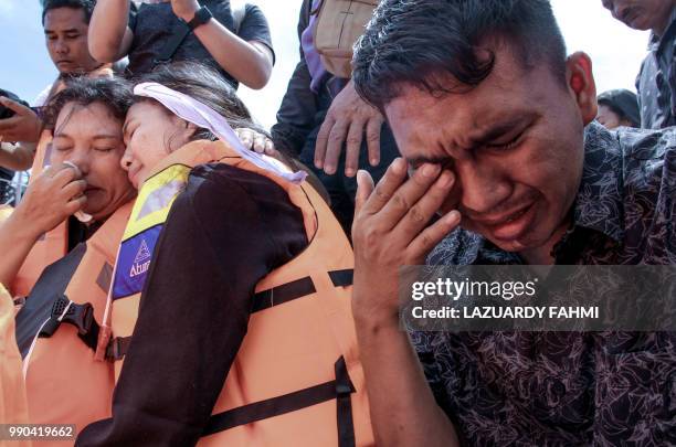 Family members of missing victims of a capsized ferry mourn during a mass memorial service at Lake Toba in North Sumatra on July 3, 2018. - The...