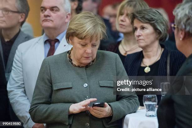 German Chancellor Angela Merkel checks her telephone during the New Year's Reception of the state counsil of the district Vorpommern-Ruegen in...