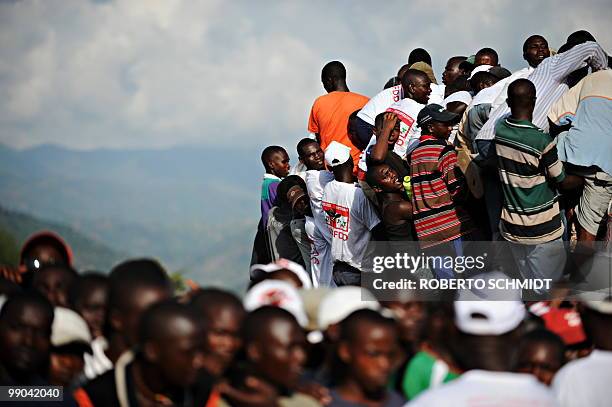 Burundian men struggle to make it on top of a truck to get a better view above a crowd of thousands during a political rally for the ruling party at...