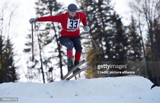 Equipped with wooden skis and wearing traditional clothing, a skier navigates the obstacle course at a nostalgic ski race in Kruen, Germany, 13...