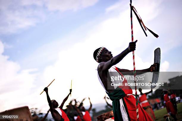 Traditional Burundian drummer dances with a shield and staff as he welcomoes a ruling party leader during a political rally at a sports field in...