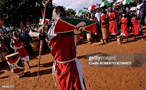 Traditional Burundian drummer dances with a shield and staff as he welcomoes a ruling party leader during a political rally at a sports field in...