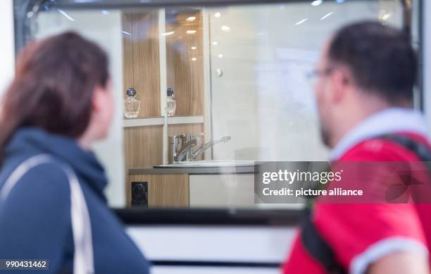 Two visitors look inside the bathroom of a caravan at the travel fair 'Caravan Motor Touristik' in Stuttgart, Germany, 13 January 2018. In the course...