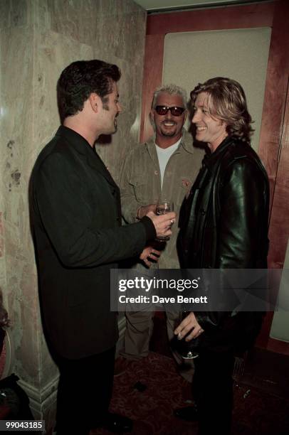 Singer George Michael chats to hairdresser Nicky Clarke during an AIDS charity fashion show at the Hilton Hotel in London, September 1998.