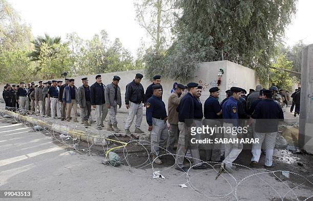 Iraqi policemen and soldiers queue outside a polling station in Baghdad before voting on March 4, 2010 in the war-battered country's second general...