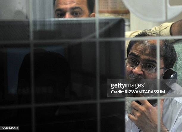 Pakistani stock dealers work at a brokerage house during a trading session in Karachi on May 12, 2010. The benchmark Karachi Stock Exchange 100-index...