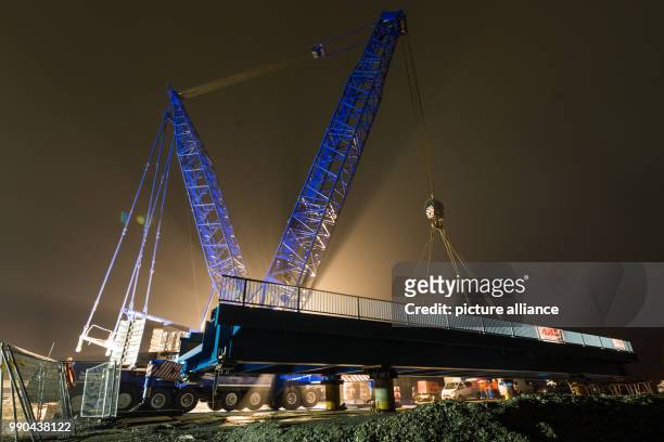 Metre-high heavy-duty crane lifts a 30-metre-long railway bridge, weighing 150 tons, over the "Ellenserdammer Tief" watercourse, near Varel, Germany,...