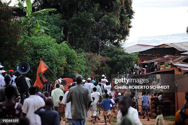 Group of followers of the main opposition party shout party slogans as they make their way past a cluster of huts in the mountains surrounding...