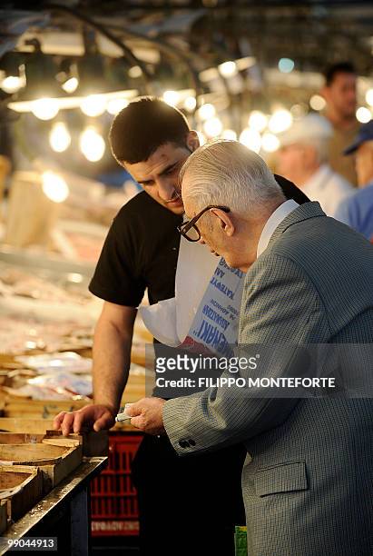 Pensioner discusses prices as he holds a five euro note while he shops in Athens central market on May 12, 2010. Greece was to receive a first dose...