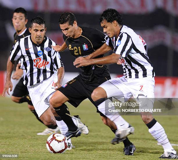 Once Caldas' Dayron Perez vies for the ball with Edgar Arnulfo Robles and Sergio Daniel Aquino of Libertad during their Libertadores Cup football...