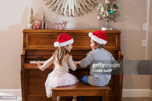 小妹妹坐在鋼琴旁戴著聖誕老人的帽子 - southern christmas 個照片及圖片檔
