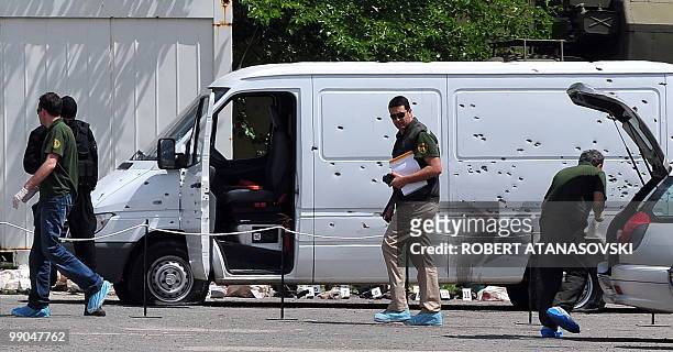 Hooded police officer stand by a van seized after a shootout, in Skopje, Macedonia, on May 12, 2010. Four people were killed in a shootout in a...