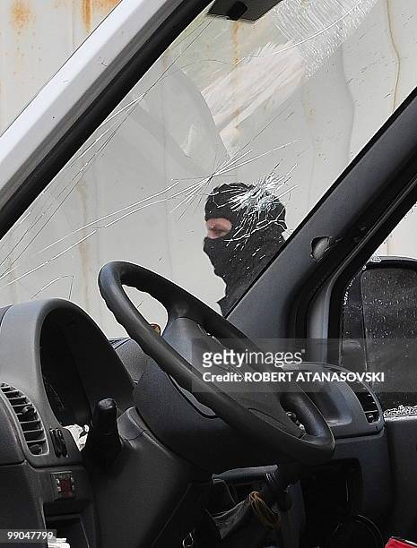 Hooded police officer stands by a van seized after a shootout, in Skopje, Macedonia, on May 12, 2010. Four people were killed in a shootout in a...