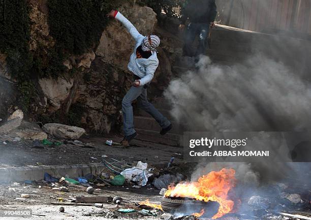 Masked Palestinian youth hurls stones at Israeli soldiers during clashes in the West Bank refugee camp of Qalandia on March 18, 2010. Tensions over...