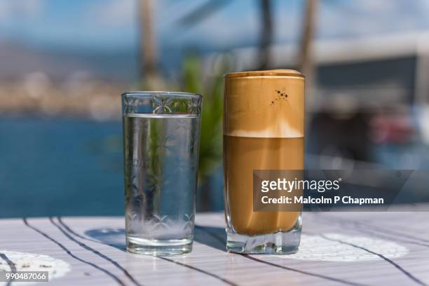 greek frappe iced coffee drink served with water, lesvos, greece - café frappé fotografías e imágenes de stock