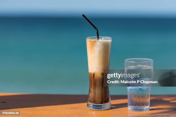 iced coffee drink by the sea - freddo cappuccino, lesvos, greece - cambodia malcolm p chapman or malcolm chapman stock-fotos und bilder