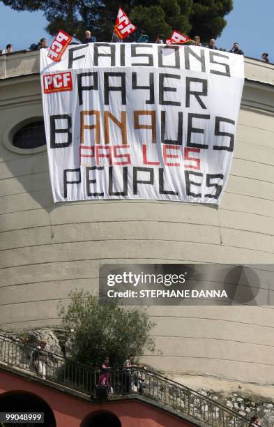 Members of the French Communist Party holds flags next to a banner reading ''banks should pay, not the people'' to denounce European austerity...