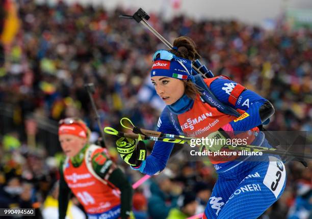 Dorothea Wierer of Italy leaves the shooting range with Franziska Hildebrand if Germany in the background during the women's mass start event of the...