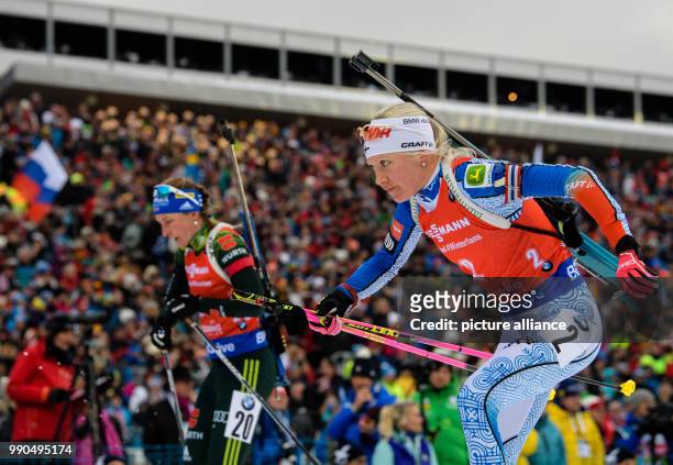 Kaisa Maekaeraeinen of Finland leaves the shooting range with Vanessa Hinz of Germany in the background during the women's mass start event of the...