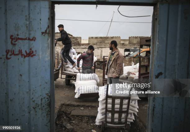 Palestinian men carry sacks of flour at the United Nations food distribution center in Al-Shati refugee camp in Gaza City, Gaza, 15 January 2018. US...