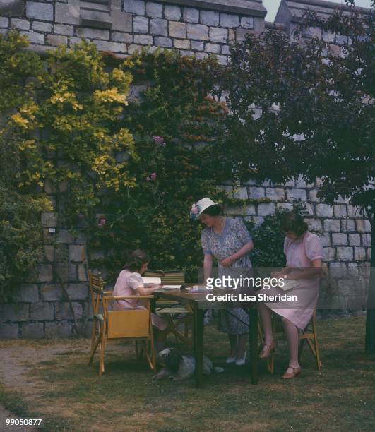 The Queen Mother watches over Princess Margaret and Princess Elizabeth reading in the grounds of Windsor Castle in England on 8 July 1941.