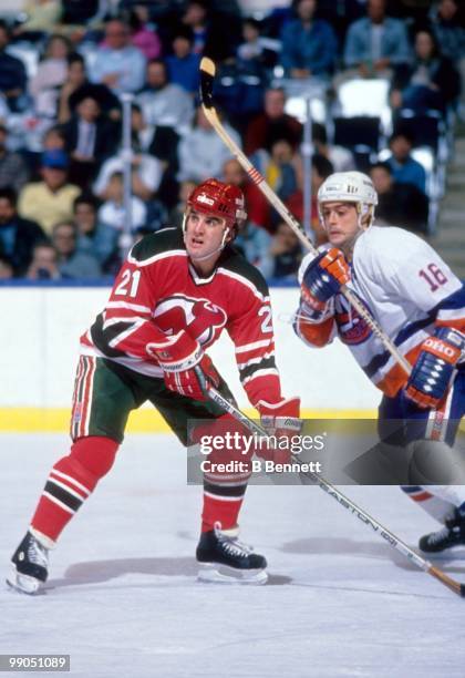 George McPhee of the New Jersey Devils defends against Pat LaFontaine of the New York Islanders during an NHL game circa 1987 at the Nassau Coliseum...