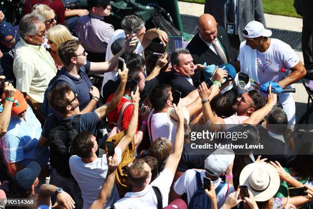 Tennis fans use their phones to take pictures of Rafael Nadal of Spain during his warm up session on day two of the Wimbledon Lawn Tennis...