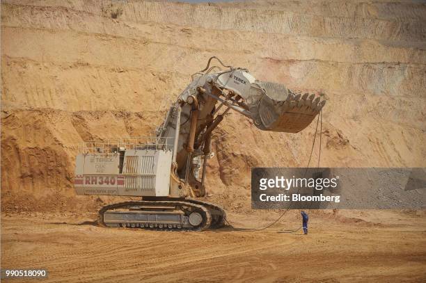 Worker assists in the operation of a giant Terex Corp. Mining excavator during the extraction of ore from the open pit at Katanga Mining Ltd.'s KOV...