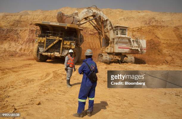 Workers stand near a Terex Corp. Mining excavator as it loads ore into a Caterpillar Inc. Truck during excavations at Katanga Mining Ltd.'s KOV...