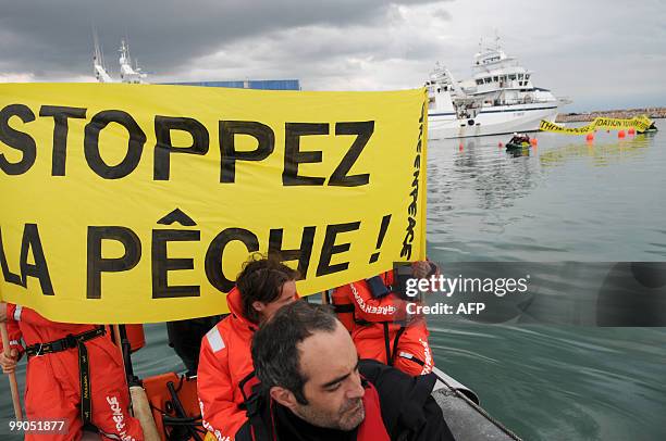 Greenpeace activists on a zodiac hold a banner reading "stop fishing" as they block Tuna fishing boats in the harbour of Frontignan, near...