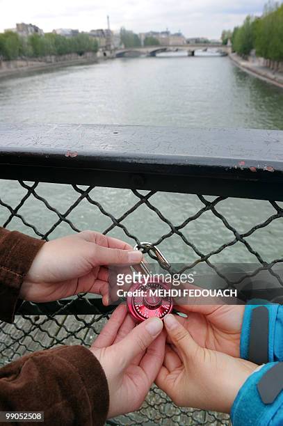 Un couple de touristes canadiens fixe un "cadenas d'amour" le 12 mai 2010 sur le pont des Arts à Paris. Ce n'est pas la mairie de Paris, encore moins...
