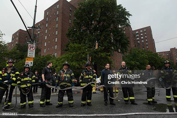 Firefighters line up with a hose line after a three-alarm fire that broke out at 502 East 14th Street, across from Stuyvesant Town in lower Manhattan...