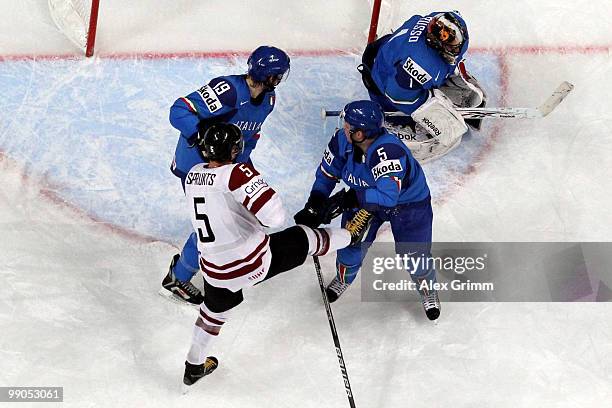 Janis Sprukts of Latvia is challenged by Matthew de Marchi, Trevor Johnson and goalkeeper Adam Russo of Italy during the IIHF World Championship...