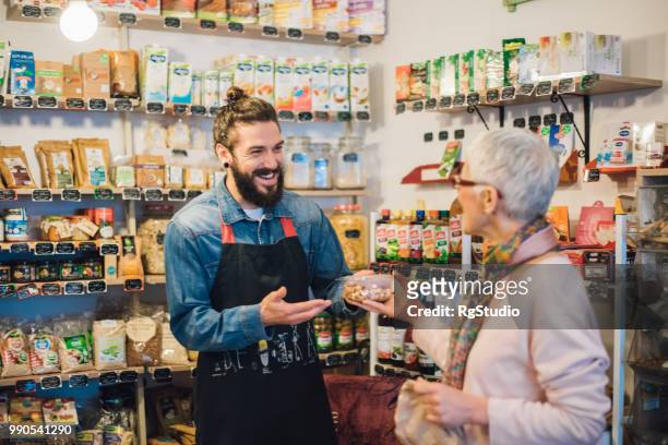 happy sales man handing a pack of nuts to a customer - retail place stock pictures, royalty-free photos & images