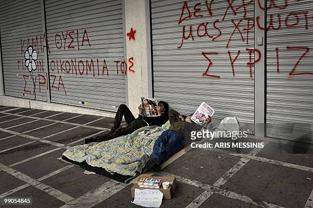 Two homeless men read newspapers outside a closed bank in central Athens on May 12, 2010. Greece was to receive a first dose of 5.5 billion euros...