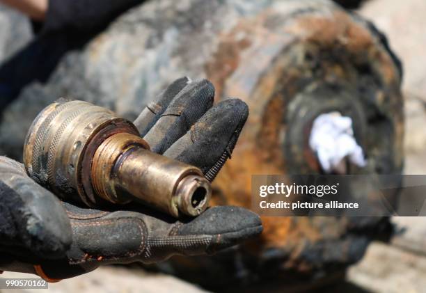 July 2018, Germany, Potsdam: Demolition expert Mike Schwitzke has deactivated the 250 kg second world war bomb and is holding the detonator in his...