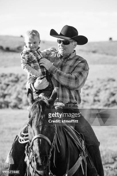 cowboy dad holding baby son while riding horse - western shirt stock pictures, royalty-free photos & images