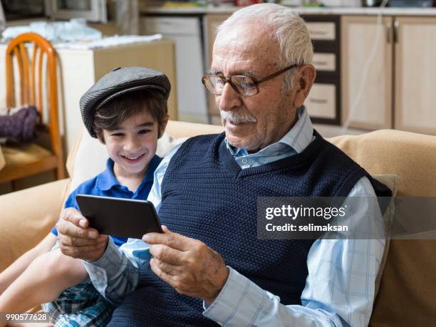 ritratto di bisnonno e nipote guardando il cellulare i̇n soggiorno - selimaksan foto e immagini stock