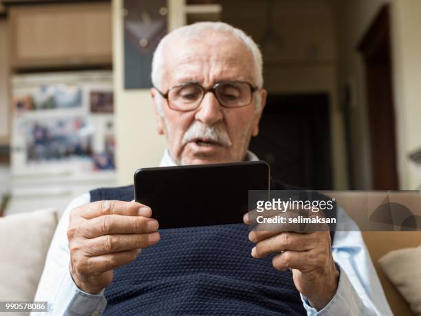 uomo anziano che tiene lo smartphone - selimaksan foto e immagini stock