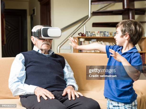 遊び心のある素晴らしい孫と vr のヘッドセットを使用して年配の男性の肖像画 - great grandfather ストックフォトと画像