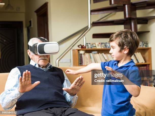 portrait of senior man using vr headset with playful great grandson - great grandson stock pictures, royalty-free photos & images