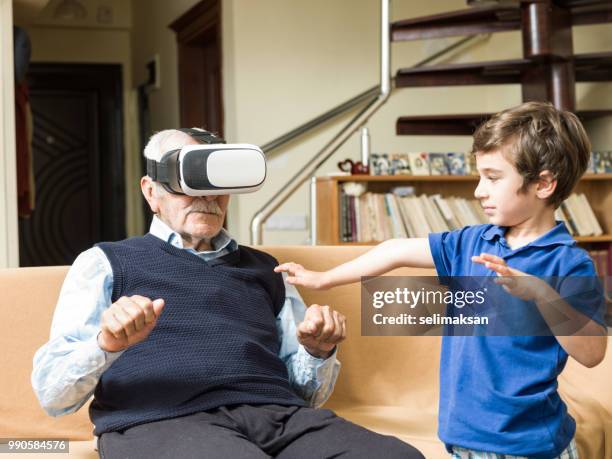 portrait of senior man using vr headset with playful great grandson - great grandson stock pictures, royalty-free photos & images