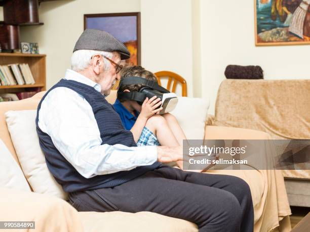 portrait of great grandfather and grandson sitting on sofa - great grandfather stock pictures, royalty-free photos & images
