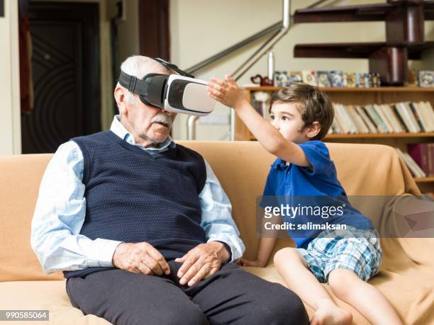 ritratto di uomo anziano che usa cuffie vr con pronipote giocoso - selimaksan foto e immagini stock