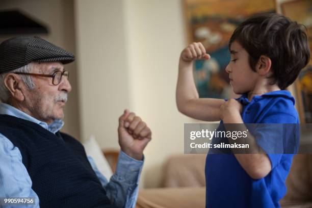 grandson showing his biceps to great grandfather - great grandfather stock pictures, royalty-free photos & images