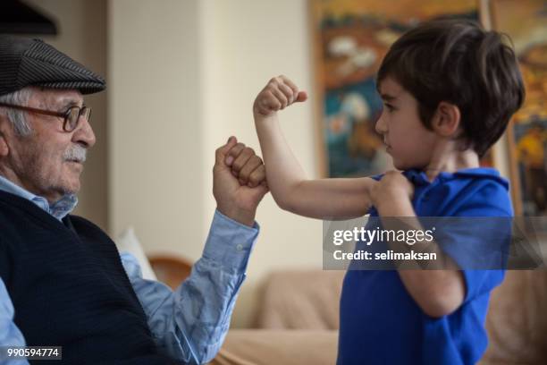 grandson showing his biceps to great grandfather - arm wrestle stock pictures, royalty-free photos & images