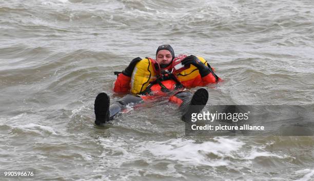 Actor Till Demtroeder, new embassador of the German Maritime Search and Rescue Service waves in the water wearing a survival suit in Cuxhaven,...