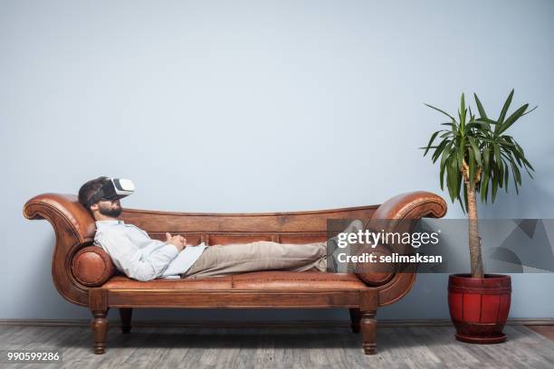 adult man with vr headset lying down on psychiatrist couch - relaxation therapy stock pictures, royalty-free photos & images